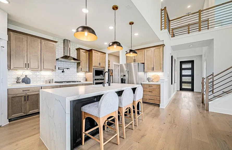 Natural wood kitchen with black and gold dome pendants, waterfall marble island