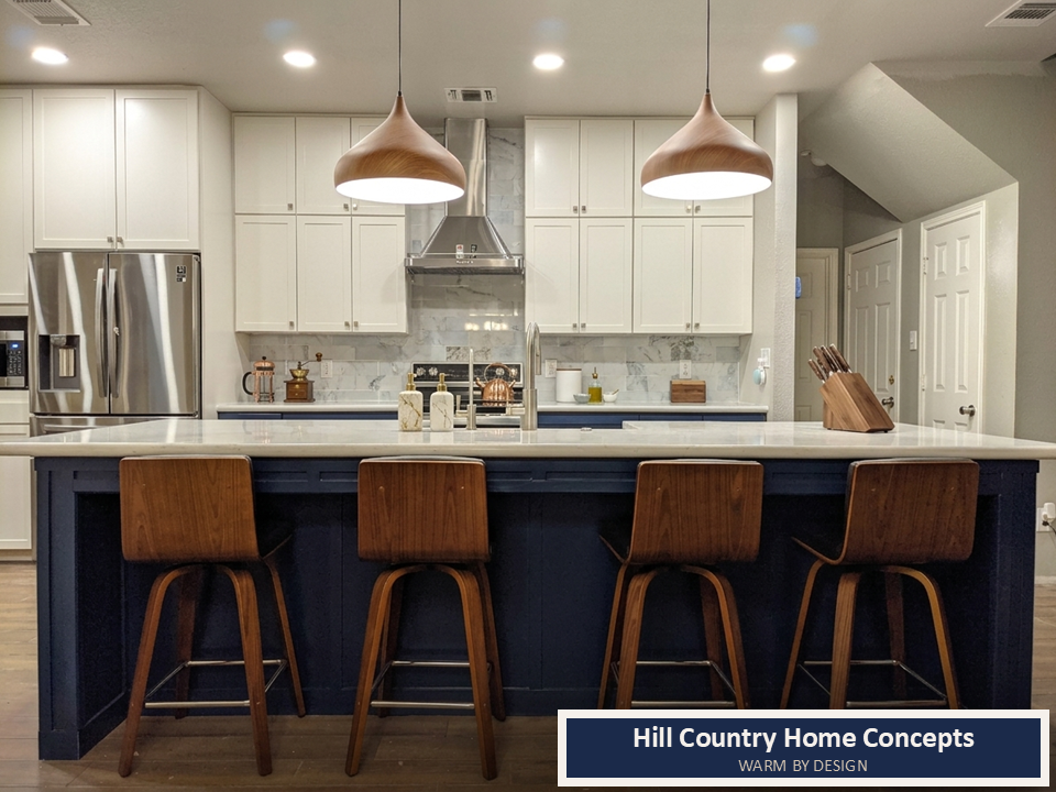 Navy blue island kitchen with copper pendants, wood bar stools, marble backsplash