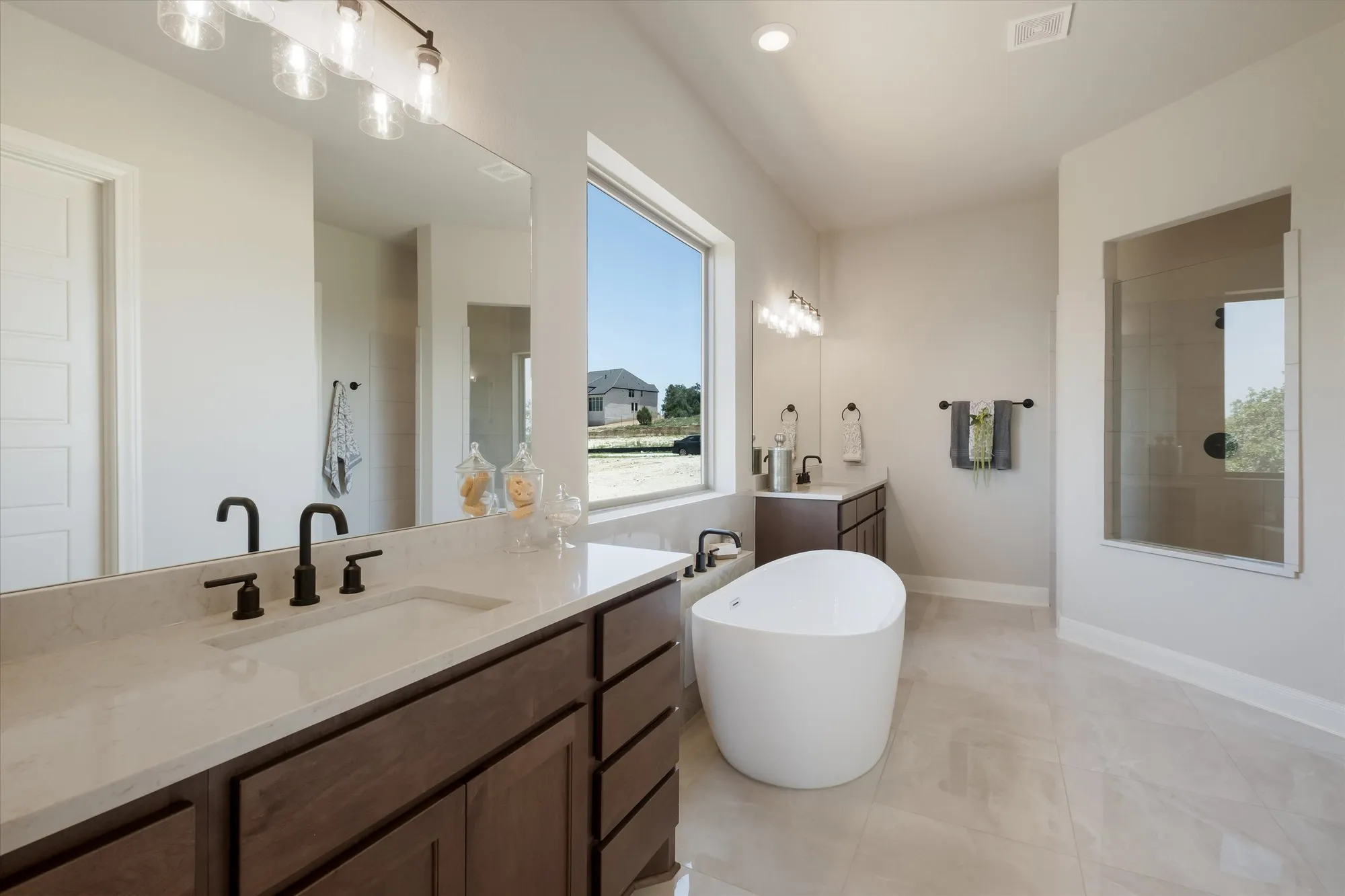 Spa bathroom with dual vanity, freestanding tub, and natural light